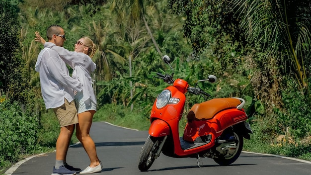 Due turisti caucasici donna uomo ballano vicino allo scooter Coppia d'amore su una moto rossa