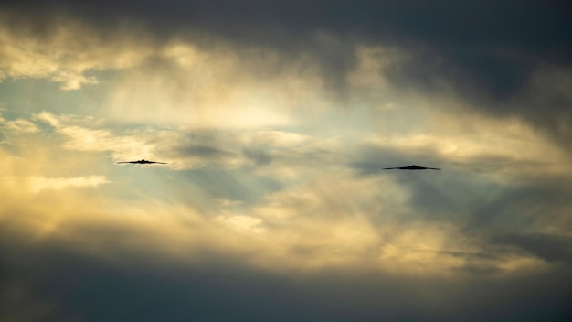 Due uccelli che volano nel cielo con il sole che splende attraverso le nuvole.