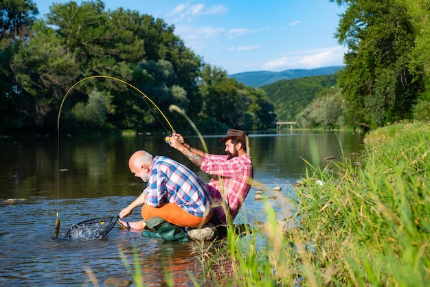 Due uomini amici pesca Pesca a mosca pescatore rende cast in piedi nell'acqua del fiume Vecchio e giovane pescatore