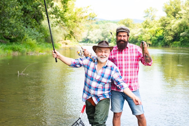 Due uomini amici pescatore pesca sul fiume vecchio padre e figlio con canna da pesca a Riverside ricreati