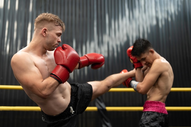 Due uomini che combattono boxe thailandese kickboxing sul ring sul palco boxer atleti che si allenano muay thai in palestra