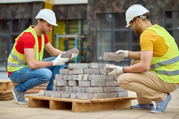 Due uomini che impilano mattoni in un cantiere edile
