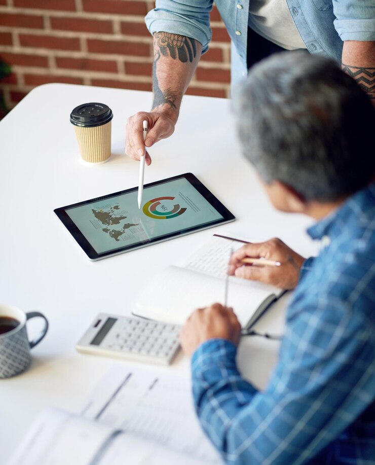 Foto due uomini d'affari che utilizzano computer tablet per discutere i dati del grafico finanziario sul dispositivo touchscreen mobile in riunione