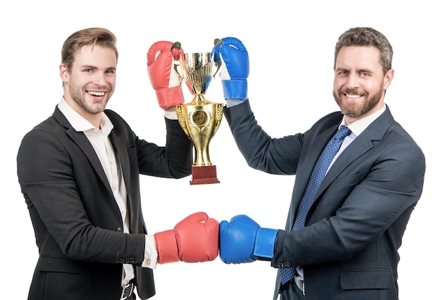 Due uomini d'affari felici in guantoni da boxe tengono la coppa del campione d'oro dopo la battaglia aziendale per il campionato di leadership