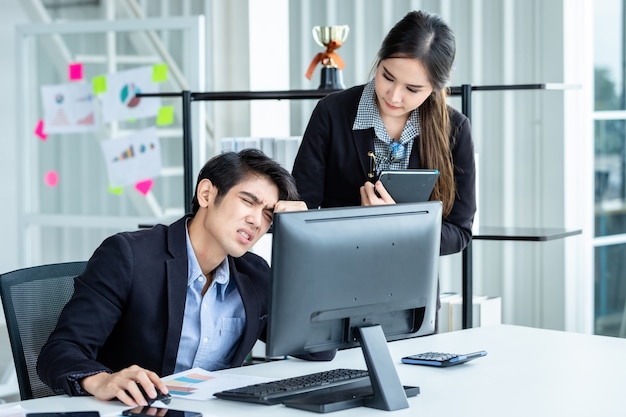 Due uomini d'affari sono stressati al lavoro con partner di donne d'affari che aiutano a formulare raccomandazioni positive lavorando con il computer su un tavolo di legno e idee alla riunione in background dell'ufficio.