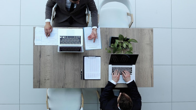 Due uomini d'affari sorridenti di successo stanno lavorando su una vista del laptop dall'alto