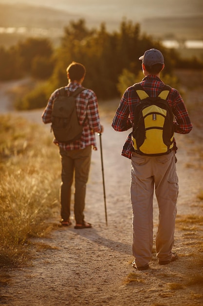 Due uomini escursionisti si godono una passeggiata nella natura al tramonto in estate