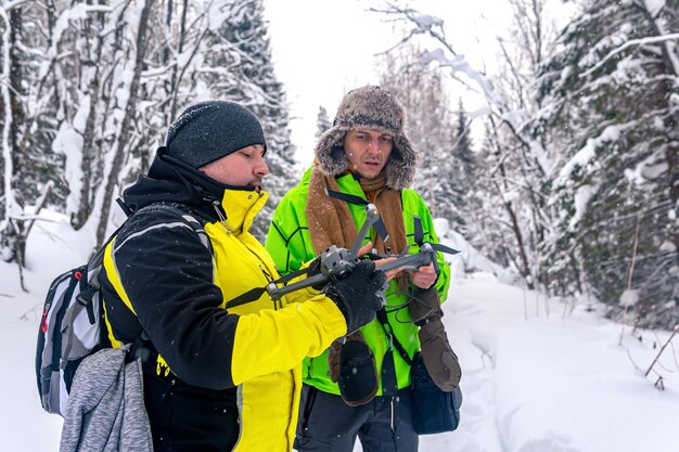 Due uomini nella foresta innevata d'inverno lanciano un quadrirotore