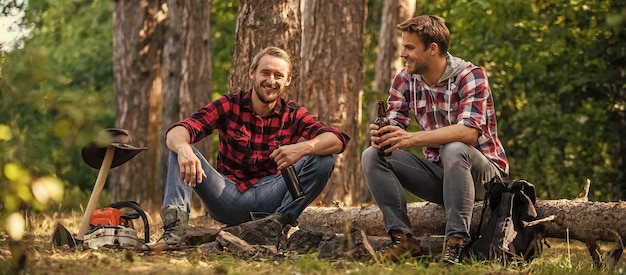 Due uomini si rilassano in escursioni nella foresta e in campeggio amicizia maschile uomo migliore amico bevono birra ranger alle attività all'aperto trascorrono il fine settimana picnic nella natura Concetto di turismo escursione e persone