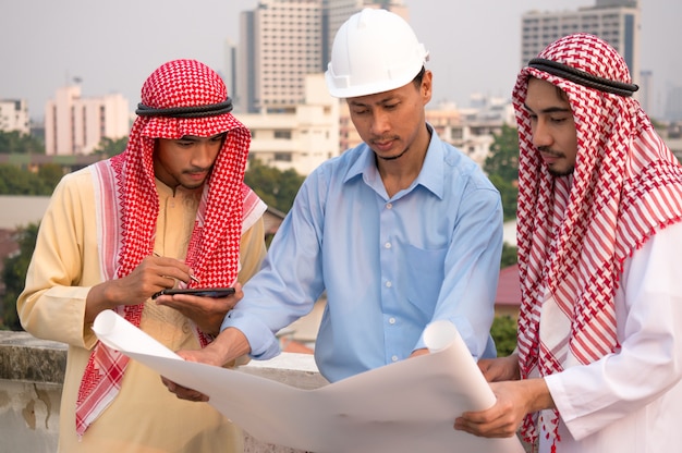 Due uomo d&#39;affari e ingegnere arabo che indossa la carta della tenuta del casco di sicurezza