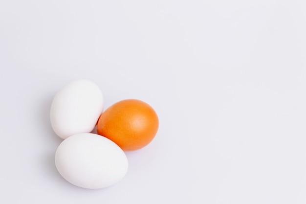 Due uova bianche e una marrone su sfondo bianco. Cibo dieta sana. Spazio per il testo.