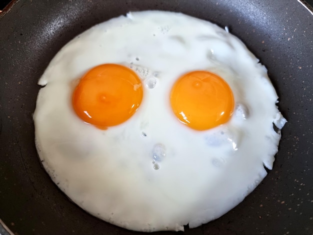 Due uova fritte in una padella di ghisa per colazione