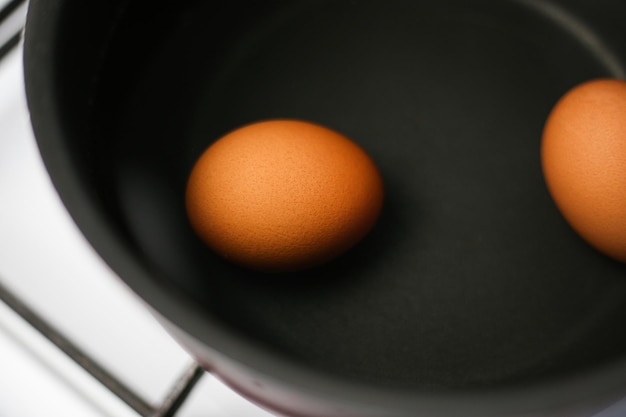 Due uova marroni in una pentola d'acqua sul fornello
