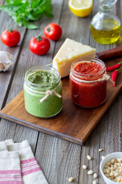 Due vasetti di vetro con pesto rosso e pesto di basilico. Cucina nazionale. Mangiare sano. Cibo vegetariano.