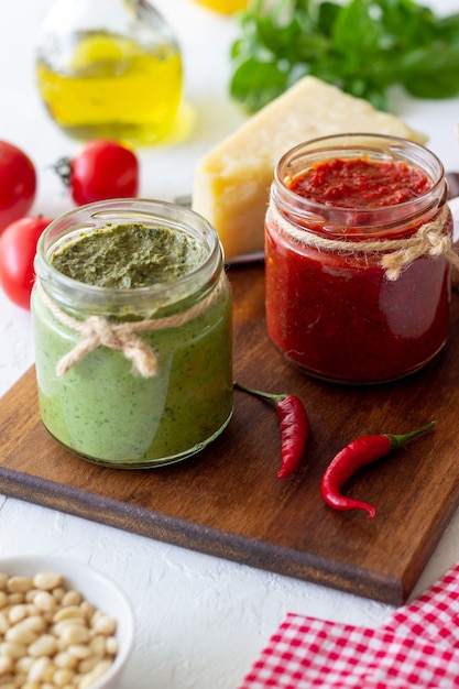 Due vasetti di vetro con pesto rosso e pesto di basilico. Cucina nazionale. Mangiare sano. Cibo vegetariano.