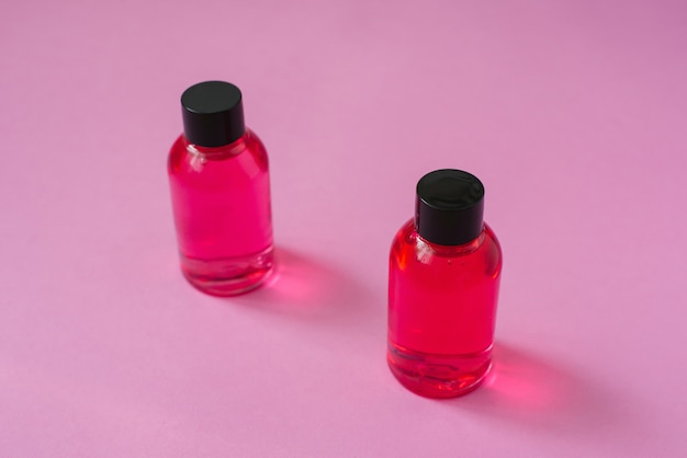 Due vasetti rosa per la cura cosmetica del corpo, viso o capelli su uno sfondo rosa. Vista dall'alto