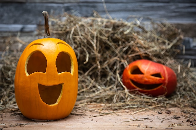 Due zucche di halloween giacciono sul fieno sullo sfondo di un muro di pietra grigia