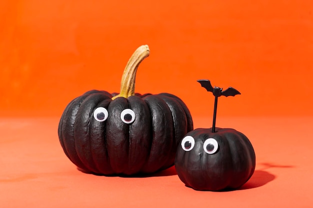 Due zucche nere con gli occhi su uno sfondo arancione mostri di zucca carta divertente di Halloween