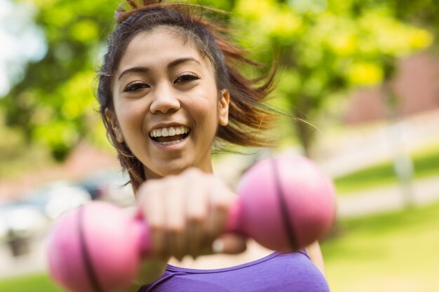 Dumbbell di sollevamento della donna in buona salute allegra in parco