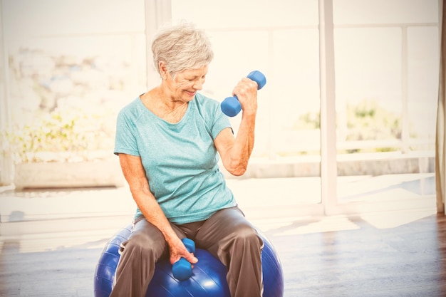 Dumbbell senior sorridente della tenuta della donna