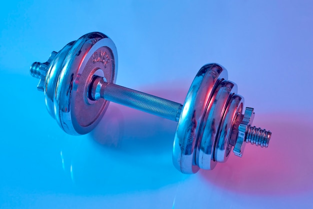 Dumbbell sul colpo dello studio di illuminazione blu e rosa del pavimento