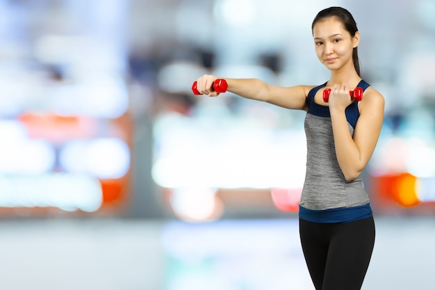 Dumbbells di sollevamento della donna felice di forma fisica