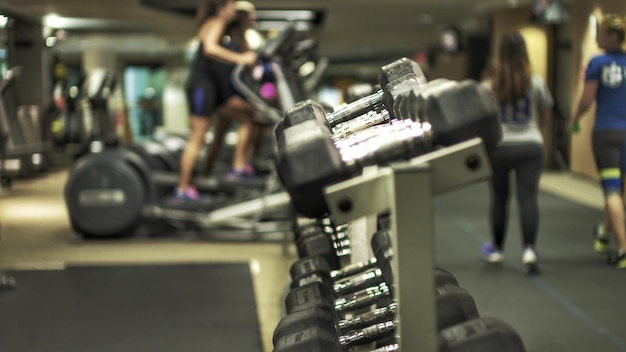 Dumbbells su rack con la gente sullo sfondo in palestra