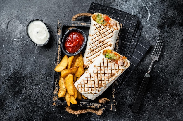 Durum doner kebab o Shawarma con insalata di verdure di carne e patatine fritte Sfondo nero Vista dall'alto