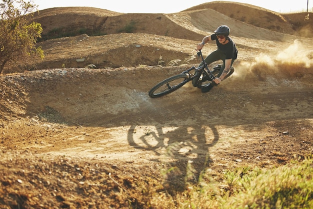 Dust mountain bike e uomo all'aperto nella natura per allenamenti o allenamenti sportivi estremi Fitness in discesa e persona di sesso maschile con coraggio o acrobazie in bicicletta per viaggi o avventure in bicicletta fuoristrada