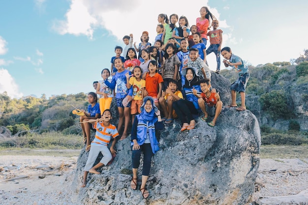 East Nusa Tenggara Indonesia I bambini fanno il tifo insieme e si divertono a giocare nella grande roccia sulla spiaggia NTT ROTE INDONESIA Aprile 2020