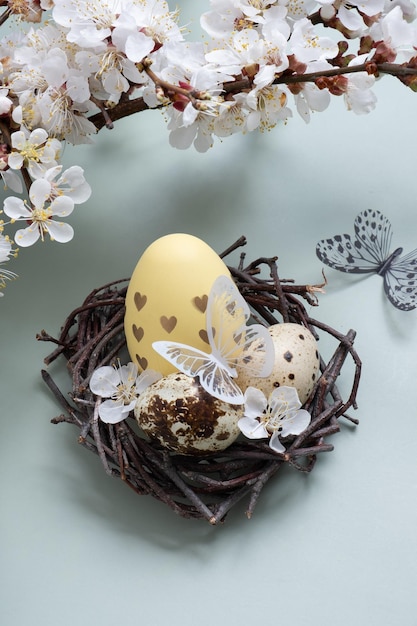 Easter eegs nel nido con fiori e farfalle su sfondo verde pastello