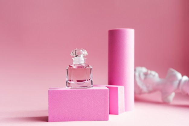 Eau de parfum rosa in una bottiglia di vetro con piedistalli rosa e sfondo rosa