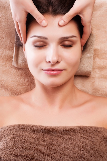 Eautiful giovane donna rilassata godere di ricevere un massaggio al viso al salone spa