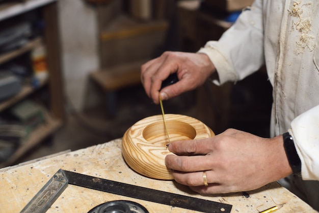 Ebanista che misura la figura in legno con il metro