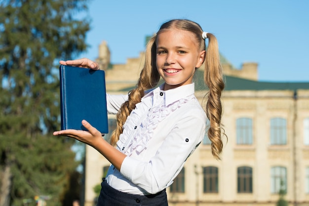 Eccellente studio della ragazza dello studente con il libro di scuola all'aperto, concetto del negozio di libri.