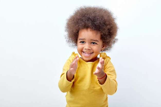 Eccitata bambina nera che applaude e applaude, felice e gioiosa, sorridente