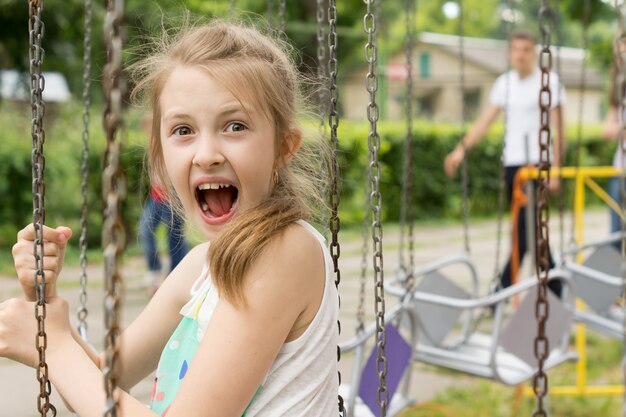 Eccitata bambina su un giro alla fiera urlando di gioia, vista ravvicinata del suo viso