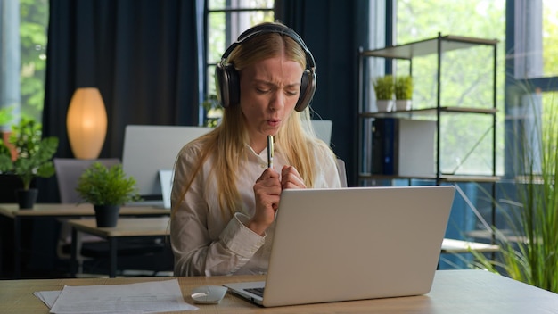 Eccitata divertente spensierata ragazza caucasica donna d'affari manager con le cuffie ascoltare musica ballare cantare