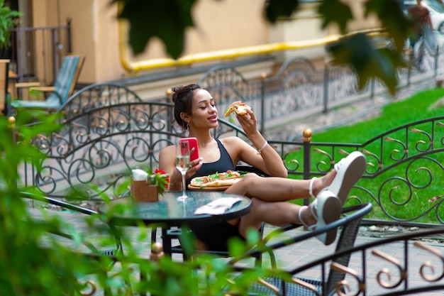 Eccitata donna bruna con labbra carnose sexy mangia un pezzo di pizza sul posto di strada per il testo