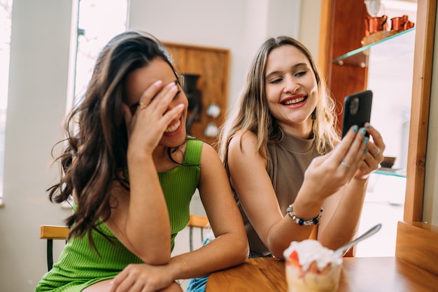 Eccitate belle due donne latine guardano video divertenti sul cellulare moderno