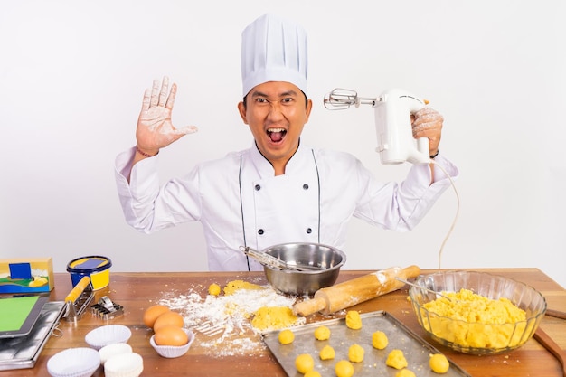 Eccitato chef maschio che tiene il mixer con un gesto sorprendente della fotocamera