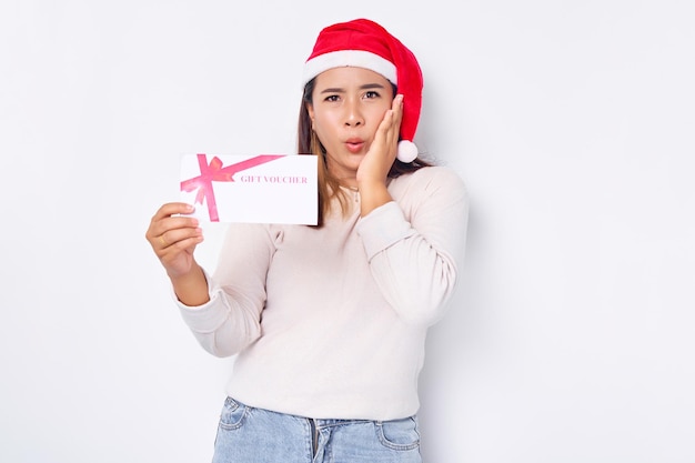 Eccitato giovane donna asiatica 20s in cappello Natale che mostra un buono regalo buono buono carta a disposizione isolato su sfondo bianco per studio Buon Natale Concept