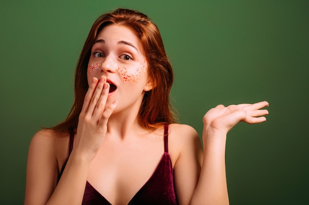 Eccitato giovane donna. Wow. Sguardo a bocca aperta. Mano sulle labbra. Oggetto virtuale nel palmo della mano.