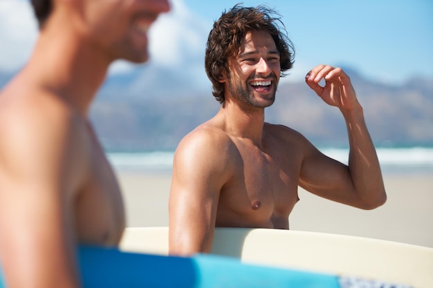 Eccitato per un po' di surf Due amici che si dirigono verso l'oceano scherzando lungo la strada