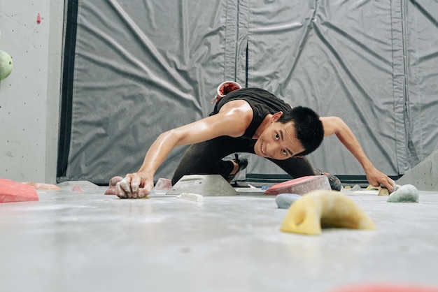 Eccitato ssweaty trong fit uomo che si arrampica sul boulderingwall, vista dall'alto