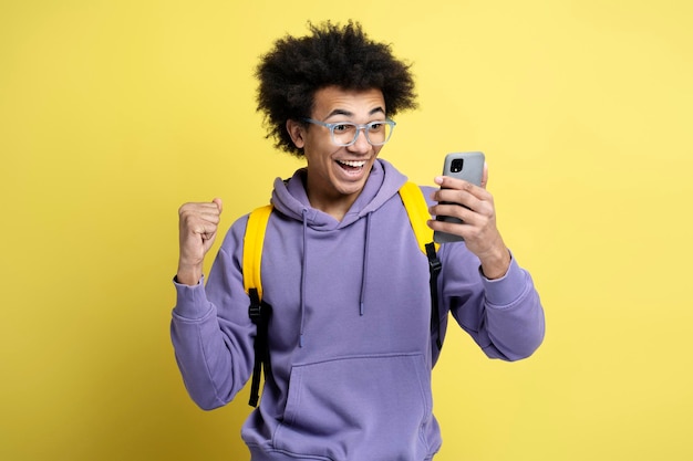 Eccitato uomo afroamericano che usa lo smartphone per giocare al successo della celebrazione del gioco mobile
