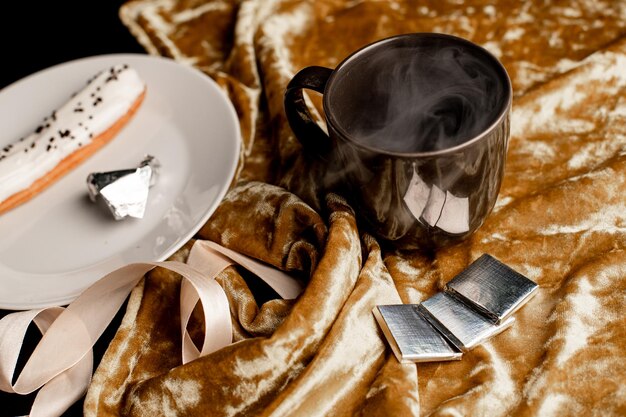 Eclair alla vaniglia su un piatto fondo oro con caffè