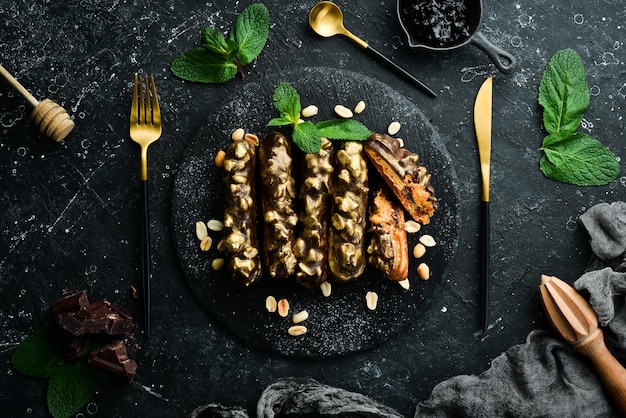 Eclair con crema al cioccolato e arachidi Dessert al cioccolato e noci su una lastra di pietra nera Vista dall'alto Stile rustico