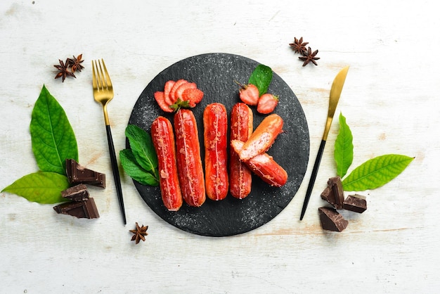 Eclair con crema di fragole Dessert alla fragola su una lastra di pietra nera Vista dall'alto Stile rustico