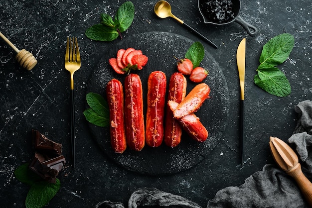 Eclair con crema di fragole dessert di fragole su un piatto di pietra nera vista superiore stile rustico